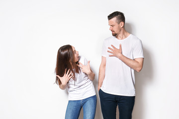 Confused young couple on light background