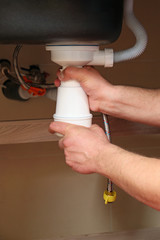 Plumber repairing sink in kitchen