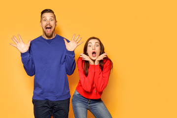 Excited young couple on color background