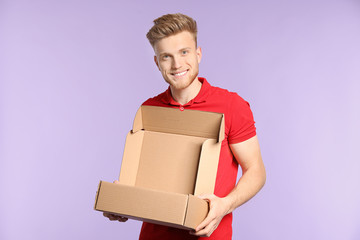 Young man with empty cardboard box on color background
