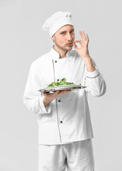 Handsome male chef with salad on white background