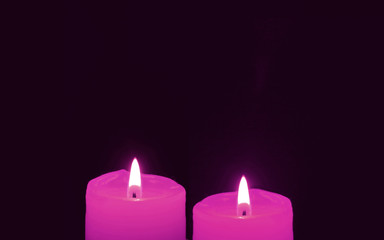 Obraz na płótnie Canvas Shining a Pair of Vivid Pink Candles on Black Background with Copy Space