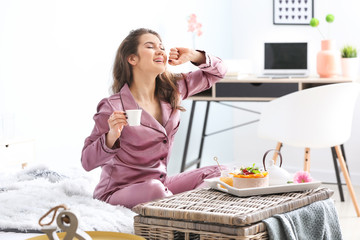 Beautiful young woman having breakfast in bed