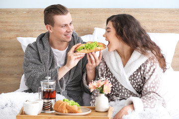 Cute young couple having breakfast in bed