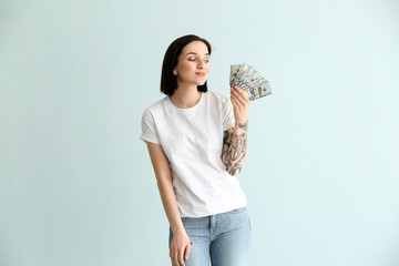 Beautiful young woman with dollar banknotes on light background