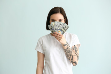 Beautiful young woman with dollar banknotes on light background