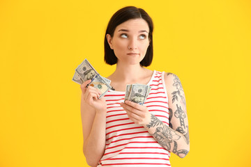 Thoughtful young woman with dollar banknotes on color background