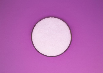 Obraz na płótnie Canvas White sea salt in round cap on a purple background