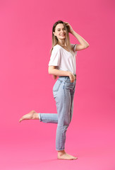 Fototapeta premium Stylish young woman in jeans on color background