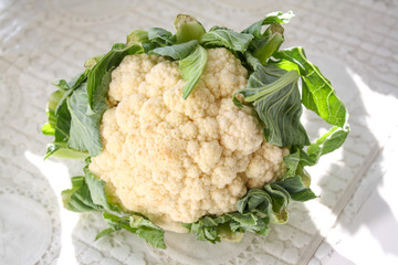 Fresh cauliflower with leaves on a white table
