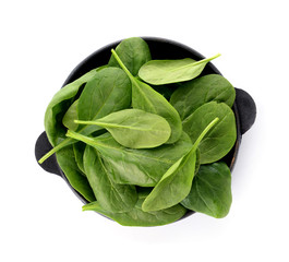 Frying pan with fresh spinach on white background
