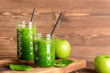 Jars of fresh smoothie on wooden board