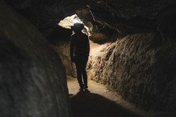 Silhouette Girl exploring huge cave. Adventure traveller dressed cowboy hat and backpack, leather jacket. extreme vacation, tourist route. ancient crystal formations, geology, village Kryvche. Ukraine