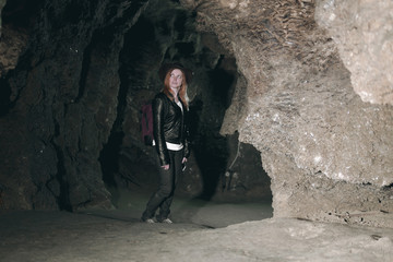 Girl exploring huge cave. Adventure traveller dressed cowboy hat and backpack, leather jacket. extreme vacation, tourist route. ancient crystal formations, geology, village Kryvche. Ukraine