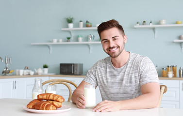 Handsome man drinking tasty milk in kitchen at home