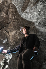 Man exploring huge cave. Adventure travellers dressed cowboy hat and leather jacket. extreme, tourist route. ancient crystal formations, geology, vertical photo. village Kryvche. Ukraine