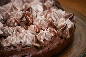 varigated frosting swirled on top of a thin single layer coffee flavored cake on a platter set on a table in a kitchen