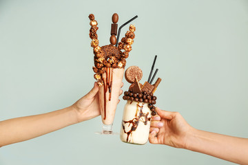 Female hands with delicious freak shakes on grey background