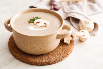 Pot of tasty mushroom cream soup on table