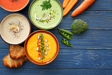 Bowls of tasty cream soups on table
