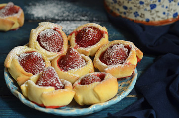 Cookies with whole strawberries on a rustic saucer on a blue background