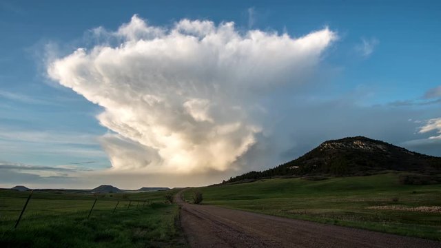 Time lapse looking down dirt road towards tall cloud structure during sunset next to Bald Mountain in Colorado.