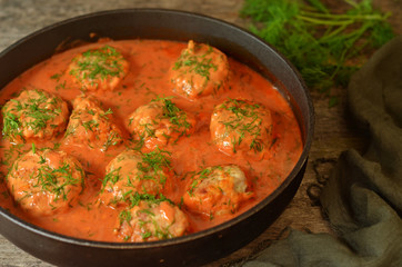 Turkey meatballs in tomato sauce in a pan on a wooden background