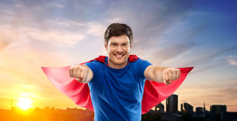 super power and people concept - happy young man in red superhero cape over sunset in city of...