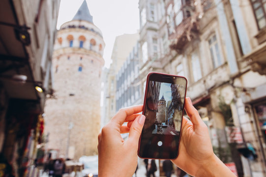 Popular tourist destination in Istanbul, Turkey. A woman makes a photo from the phone camera in Istanbul. Man in Istanbul taking pictures with a smartphone in front of the Galata Tower