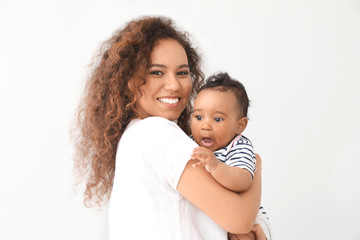 Happy African-American mother with cute little baby on white background