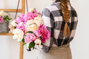 Female florist with beautiful bouquet of peonies in shop