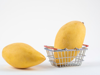 Ripe mangoes shopping concept with shopping cart, basket on the white background