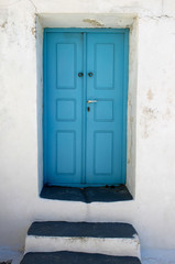 Beautiful picturesque turquoise blue wooden door and white wall. Entrance. Mediterranean motif.