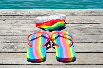 rainbow-patterned flip-flops and swimsuit on dock
