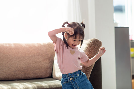Happy Asian child having fun and dancing in a room
