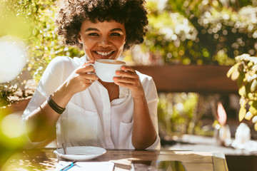 Cheerful african woman having coffee