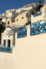 Santorini oia fira caldera street view. White traditional greek houses on the hill. Sunny day in the cycladic village. Blue wooden banister.