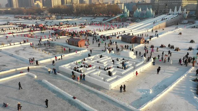 Tilting drone shot of Chinese tourists and locals getting lost in a classic maze made of snow during the Harbin ice and snow festival