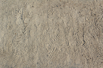 abstract background of shoes prints going in different direction on sand surface