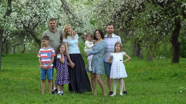 families, parents with children pose in front of camera in spring garden