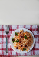 salad of fermented cabbage and cranberries on a plate and a fork stand on a white table on a napkin