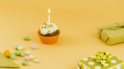 Birthday cupcake with candle and gifts