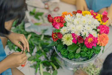 Students help each other to create a flowers tray with pedestal  for The Teachers’ Day