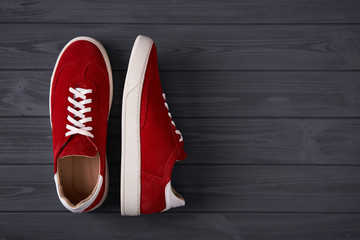 Top view of casual red suede trainers on grey wooden planks