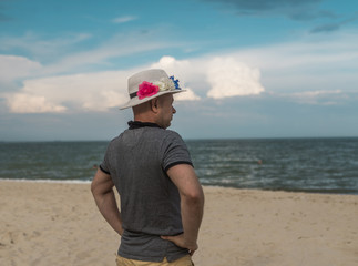 man in a hat with flowers on the beach