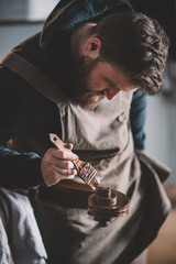 Young luthier working in his workshop, building a double bass