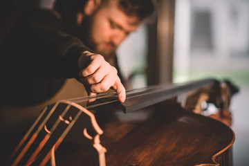 Young luthier working in his workshop, building a double bass