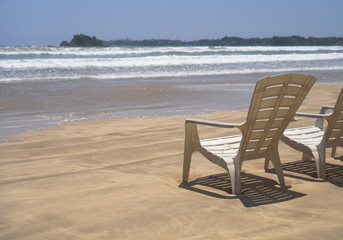 Beautiful Sri Lankan view of the Indian Ocean with sun loungers on the beach. Summer holidays in Asia. Stock photos