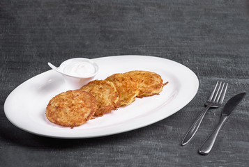 Draniki - potato fritters. potato pancakes with sour cream sauce. The national dish of Belarus, Ukraine and Russia. Restaurant, food menu, recipe, cafe concept.