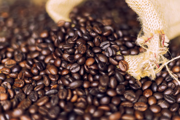 Roasted coffee beans spread out from coffee sacks